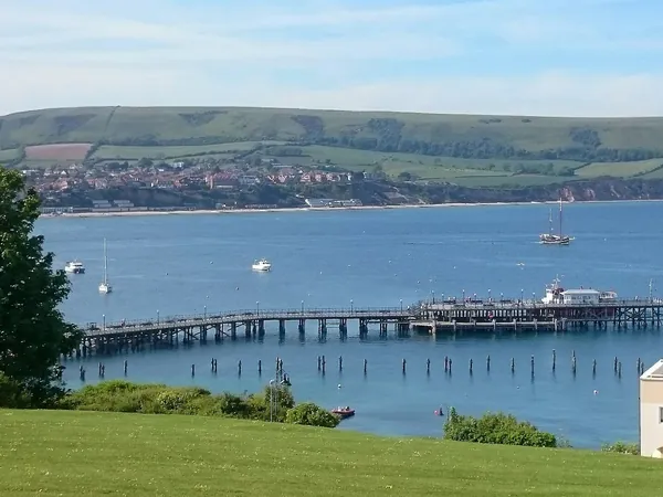 Swanage Pier stretching into Swanage Bay with the Purbeck hills behind