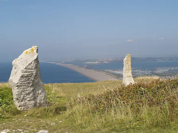 Standing stone sculptures at Tout Quarry Sculpture Park on Portland with Chesil Beach below