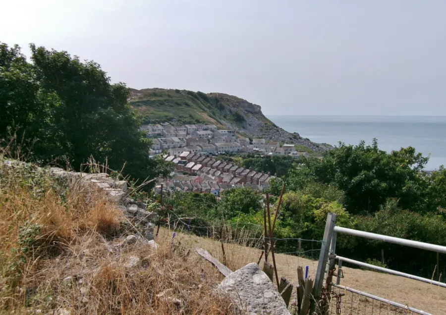 Terraced rooftops of Fortuneswell on the Isle of Portland seen from the hillside above, with the sea beyond