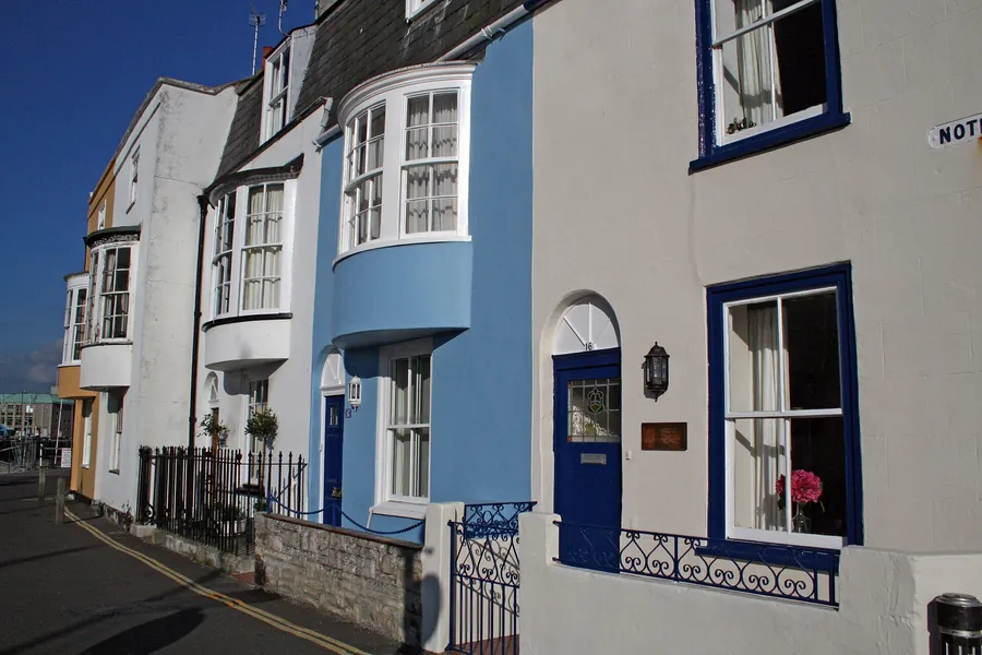 Painted three-storey terraced houses with bay windows and slate roofs on Nothe Parade, Weymouth