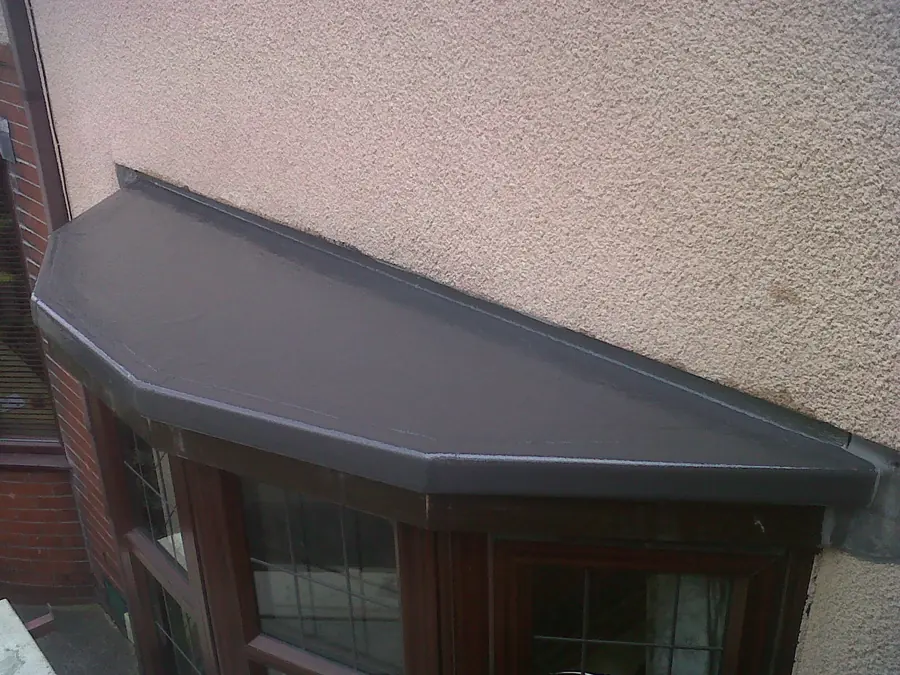 Bay window roof finished in dark GRP fibreglass with a neat formed edge against a rendered wall