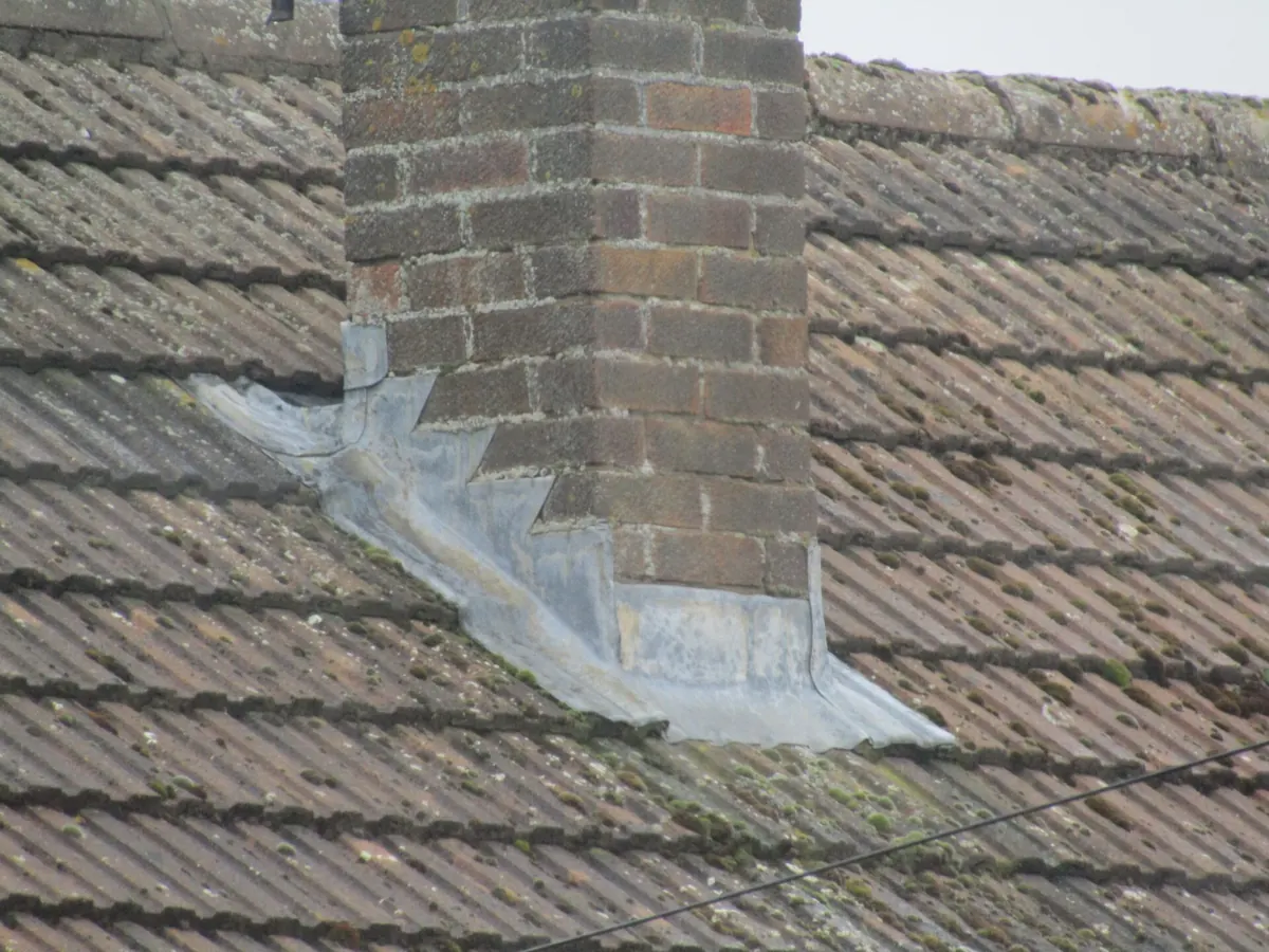Stepped lead flashing dressed around a brick chimney stack on a concrete tiled roof