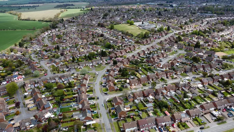 Aerial view over rows of tiled semi-detached and terraced house roofs on an English housing estate