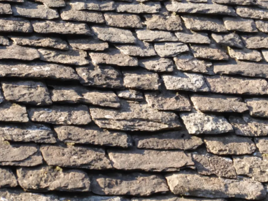 Close-up of weathered natural stone roof slates laid in diminishing courses
