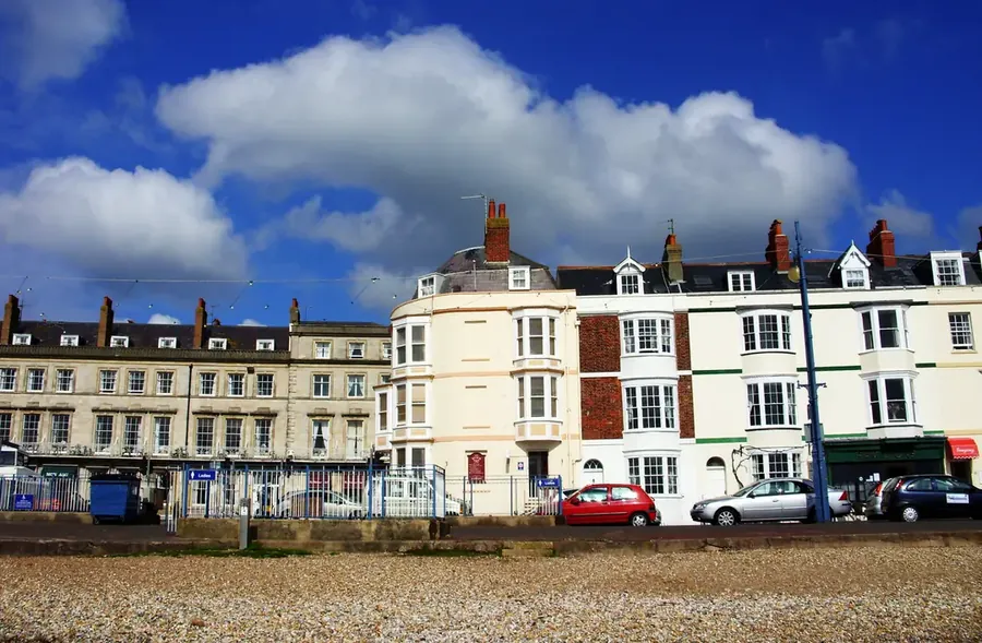 Row of Georgian and Victorian seafront terraces with slate roofs seen across the beach on Weymouth Esplanade